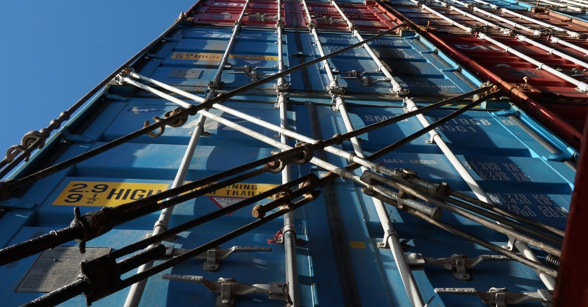 Multiple shipping containers in different colors stacked on top of each other and secured by load lock bars. Multiple shipping containers in different colors stacked on top of each other and secured by load lock bars.